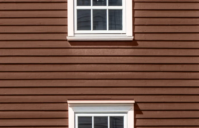 clapboard siding two floors of windows on a red wooden facade