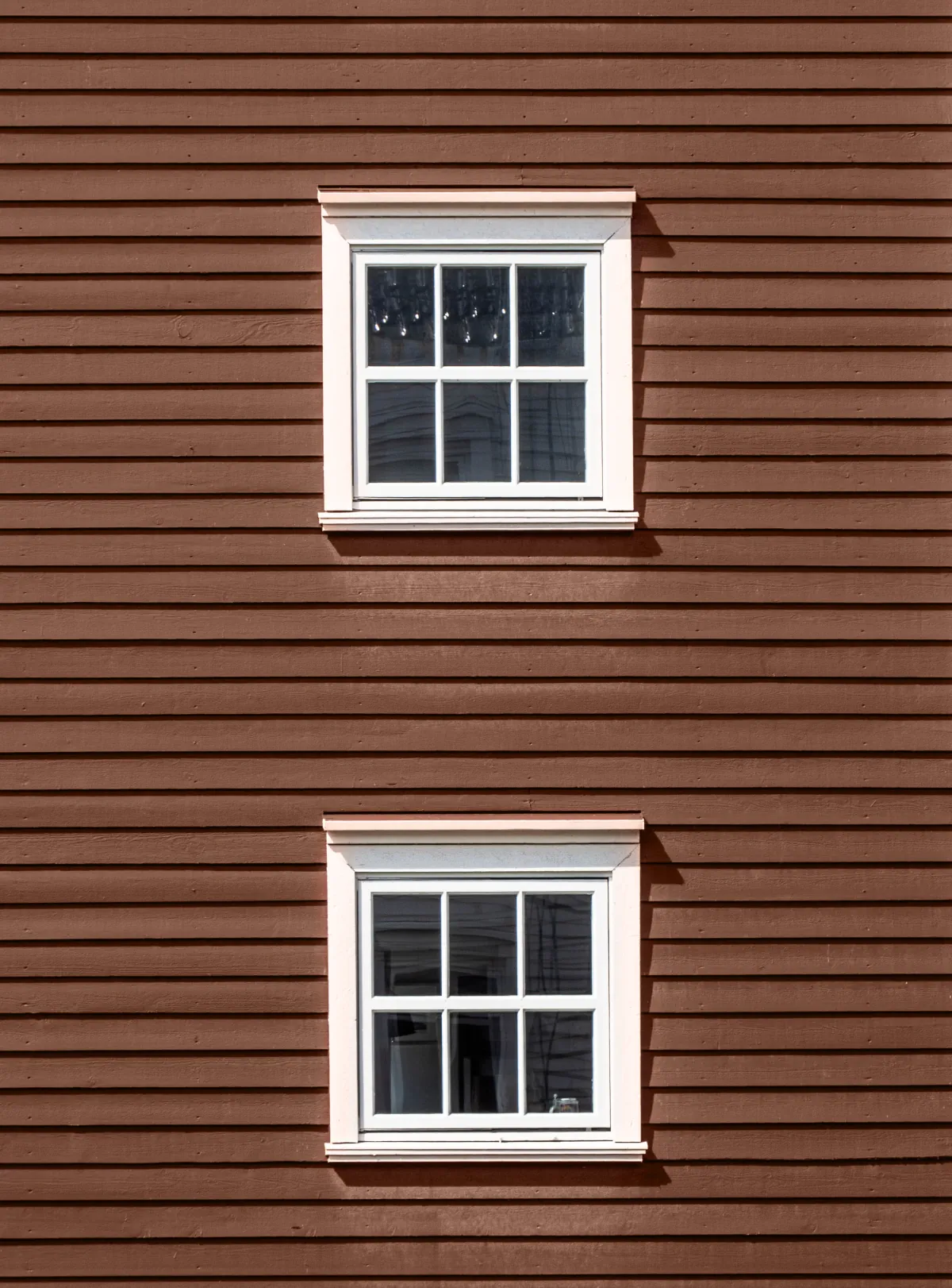 clapboard siding two floors of windows on a red wooden facade