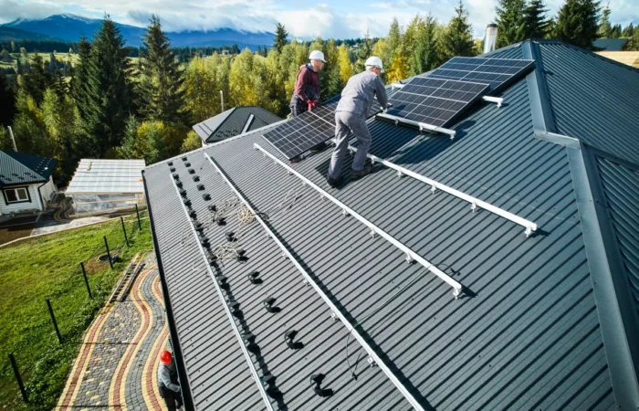 metal roof installation technicians carrying photovoltaic solar module whi