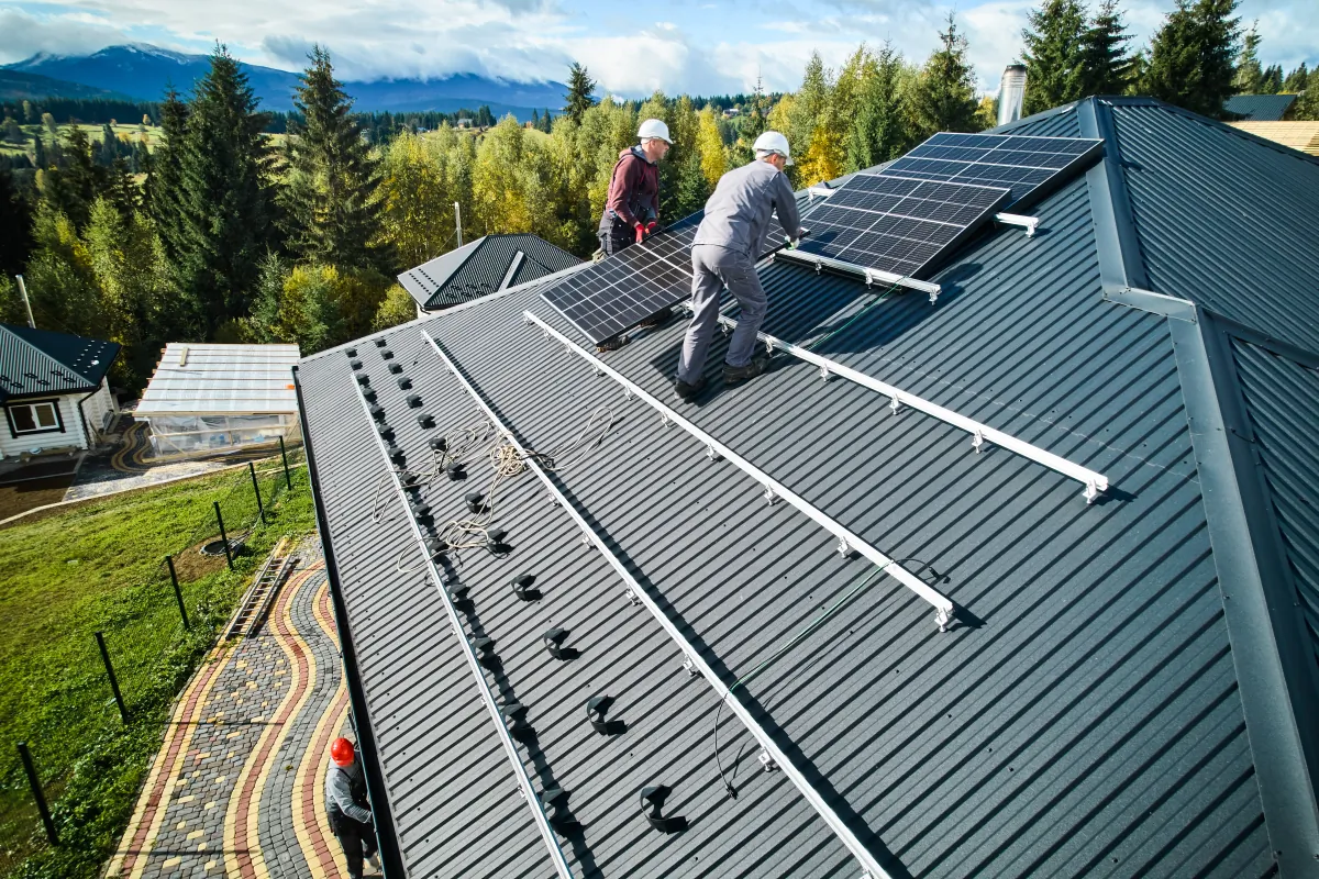 metal roof installation technicians carrying photovoltaic solar module whi