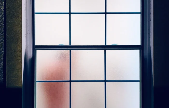 single hung window adult taking a shower behind the fogged glass wind