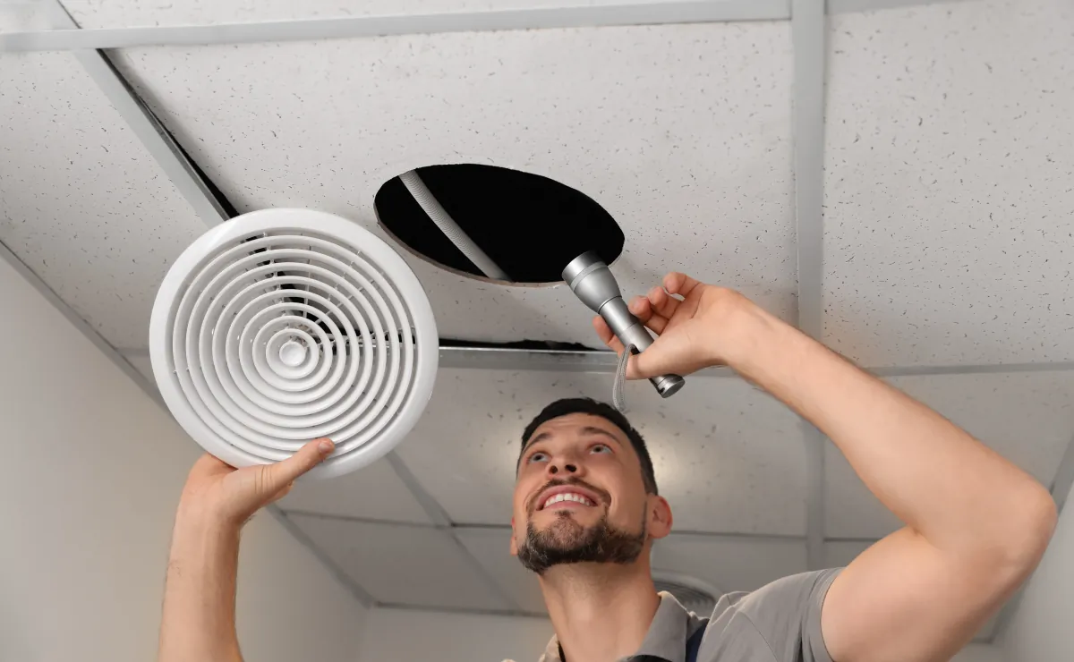 bathroom exhaust fan repairman with flashlight fixing ventilation syste