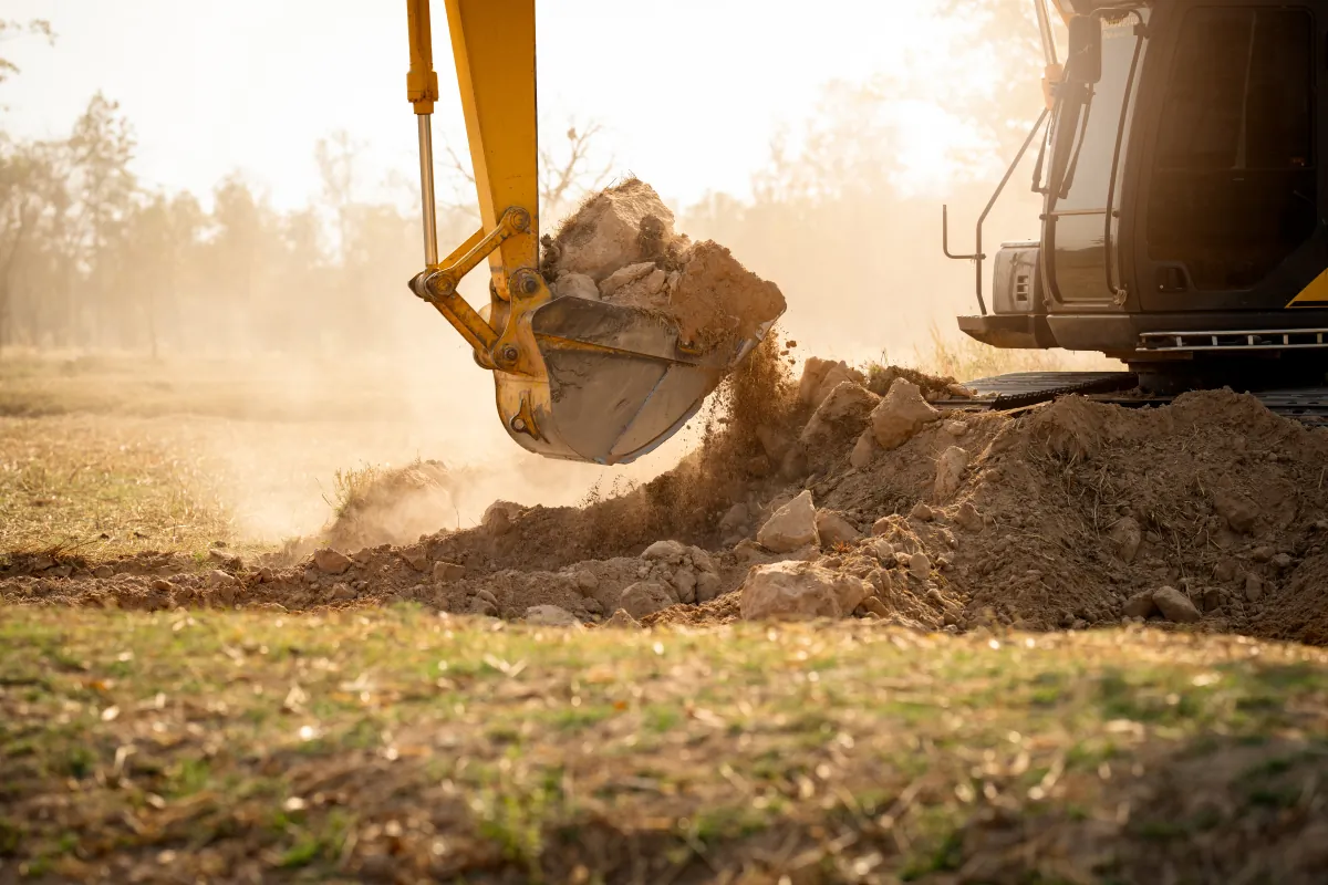 Backhoe working within a measured excavation area with site-access constraints