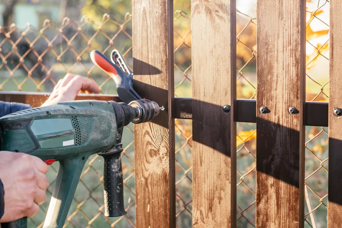 Carpenter using a drill during fence installation