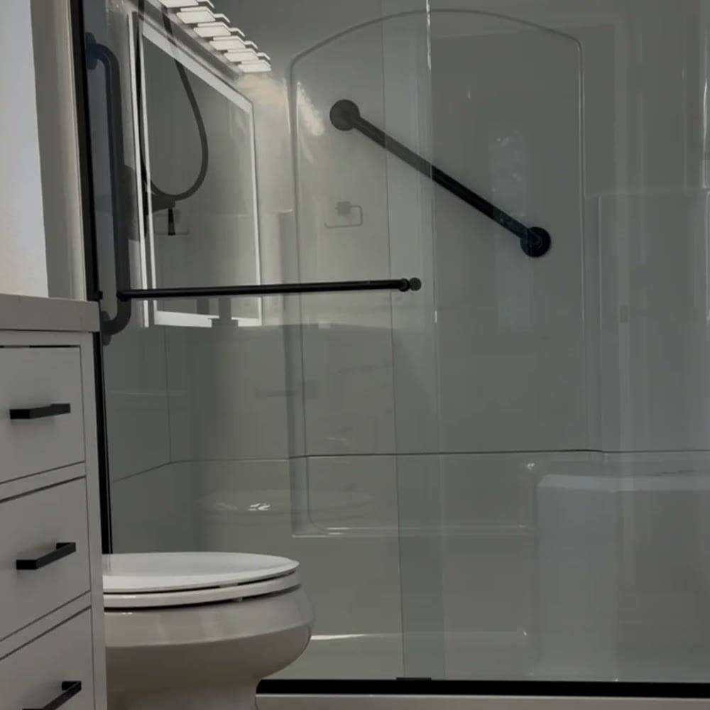 Completed bathroom remodel with glass shower enclosure and black fixtures