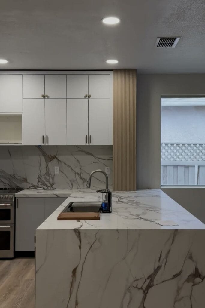 Completed kitchen remodel with waterfall quartz island and white cabinetry