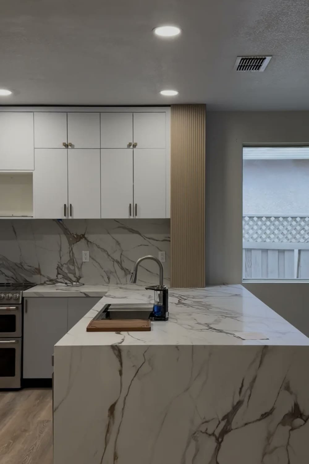 Completed kitchen remodel with waterfall quartz island and white cabinetry