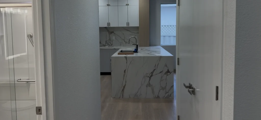 Finished kitchen viewed from the hallway with tall cabinetry, quartz surfaces, and