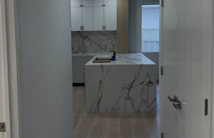 Finished Roseville kitchen viewed from the hallway with tall cabinetry, quartz surfaces, and a bright open layout.