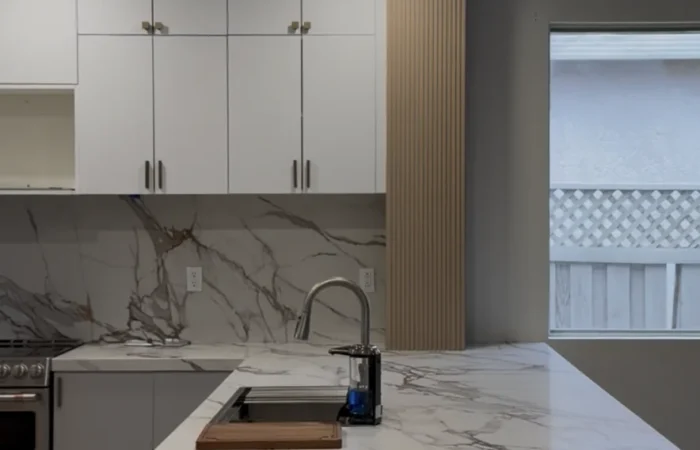 Portrait view of the completed kitchen island, quartz waterfall edge, cabinetry, and recessed lighting in Roseville, CA.