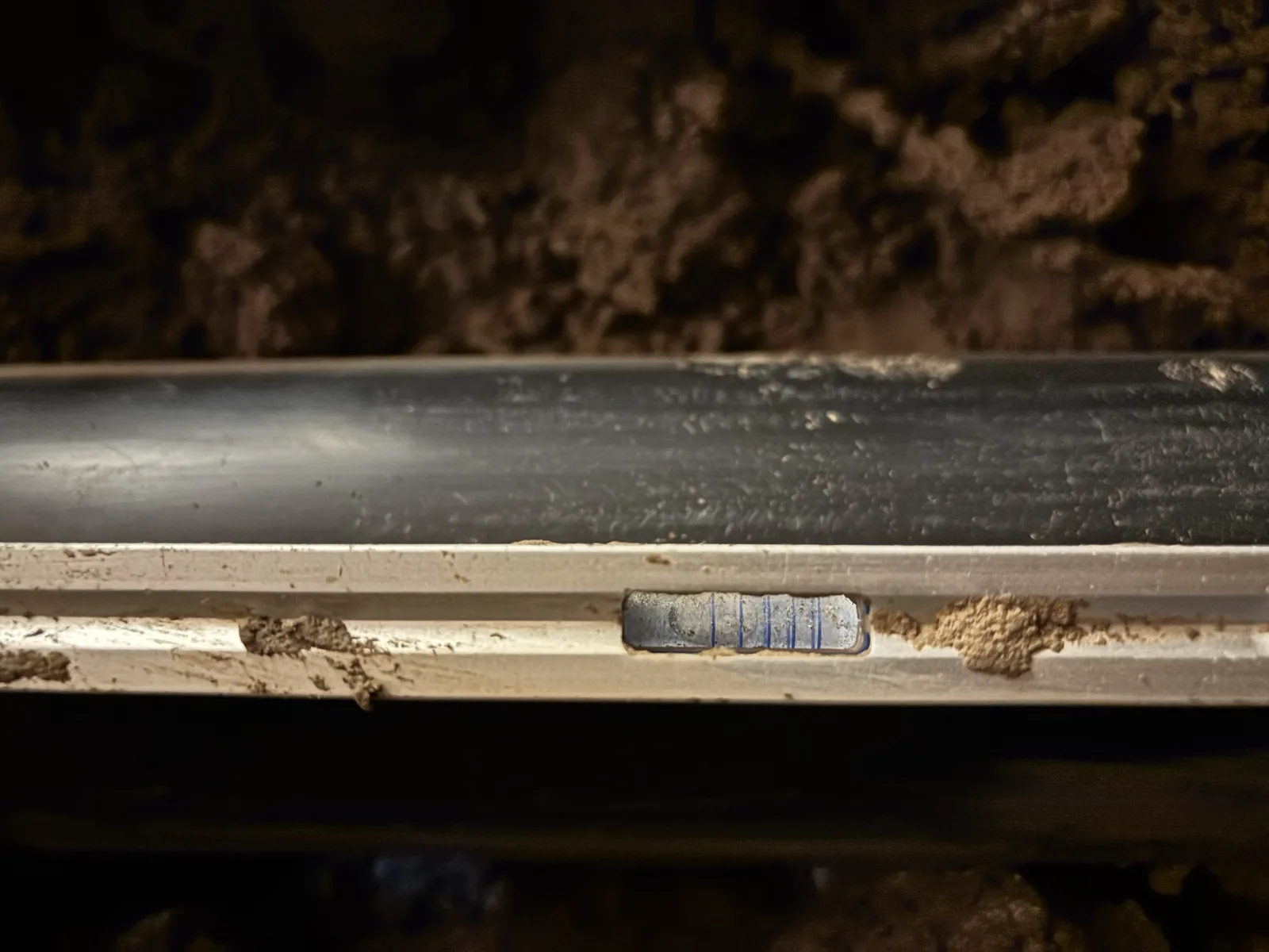 Level placed against new drain piping during crawlspace installation checks.