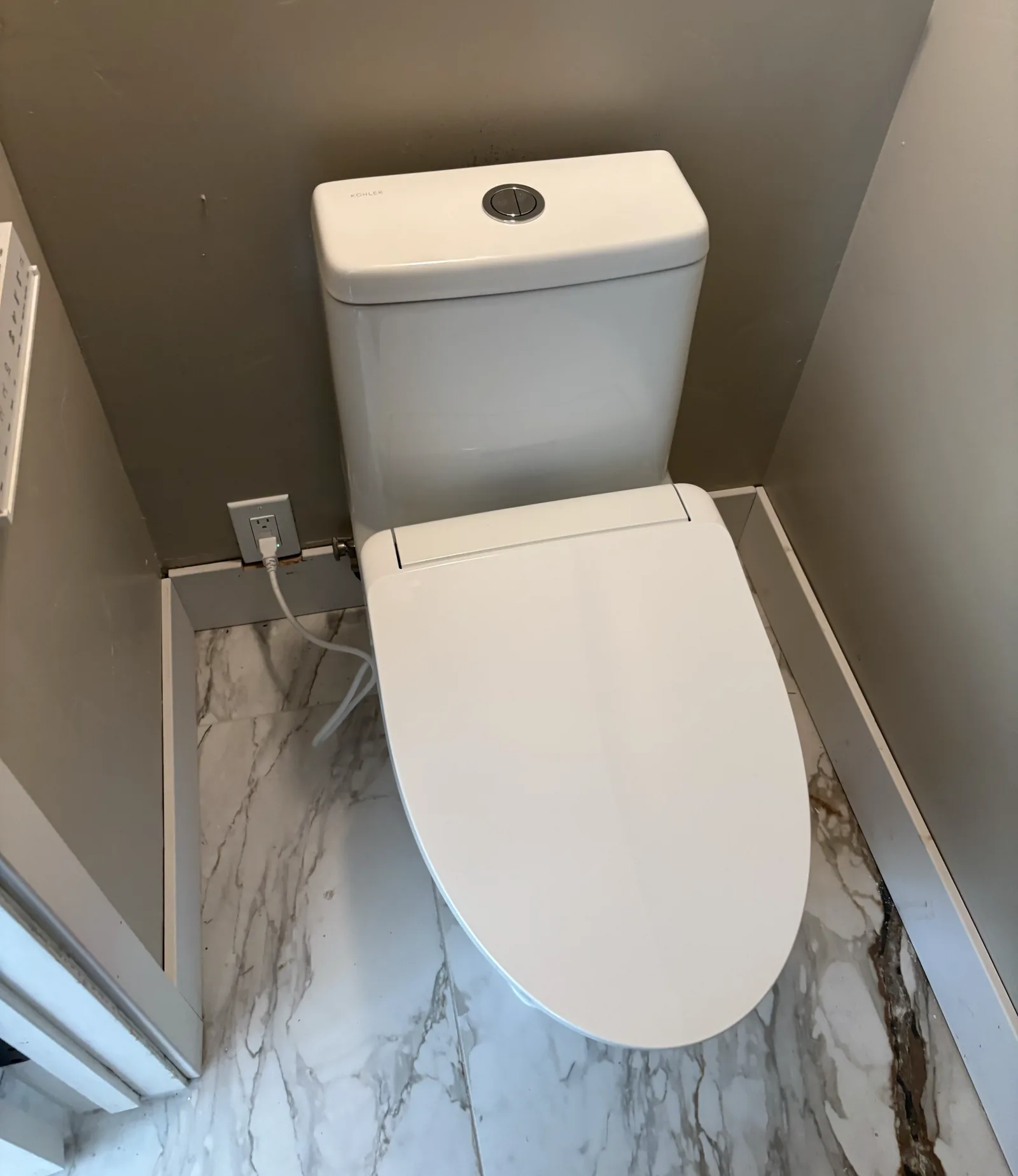 Installed electronic toilet with nearby electrical receptacle and water connection in a USC bathroom remodel.