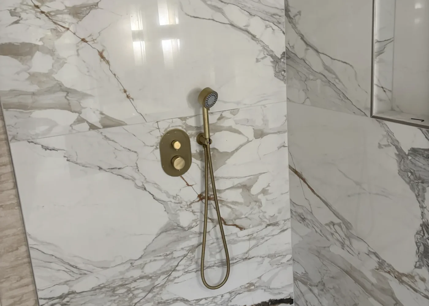 Completed marble-look shower with overhead and handheld shower fixtures in a USC bathroom plumbing remodel.