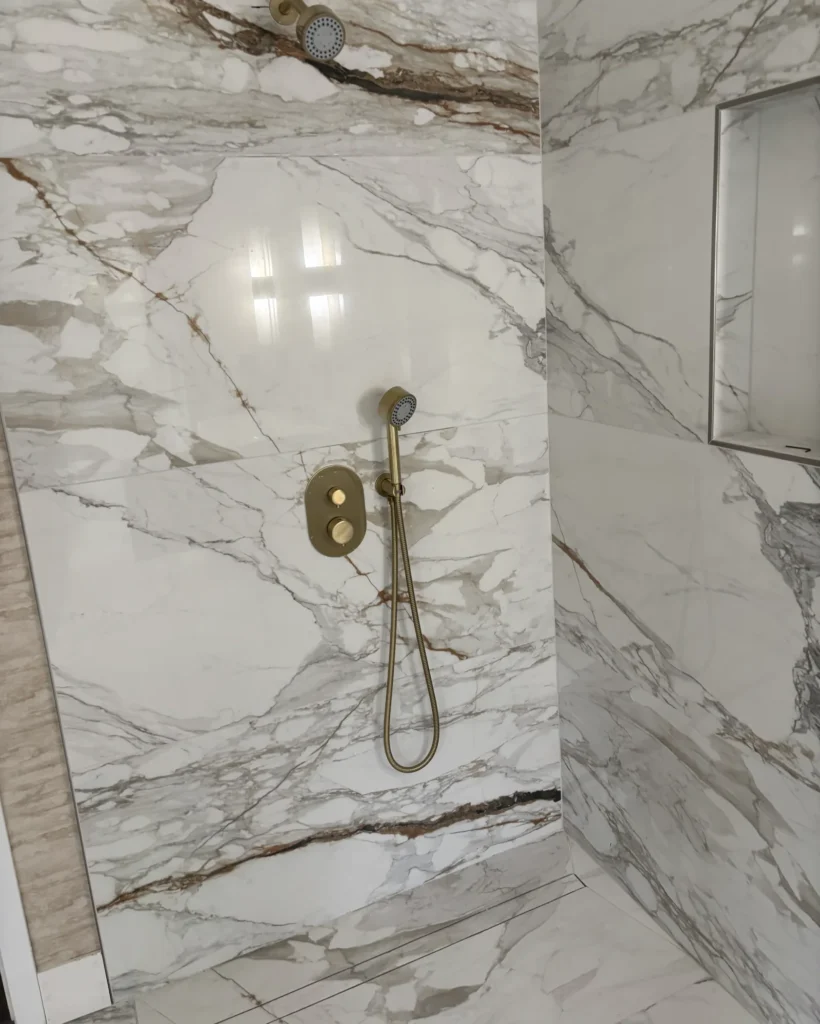 Completed marble-look shower with overhead and handheld shower fixtures in a USC