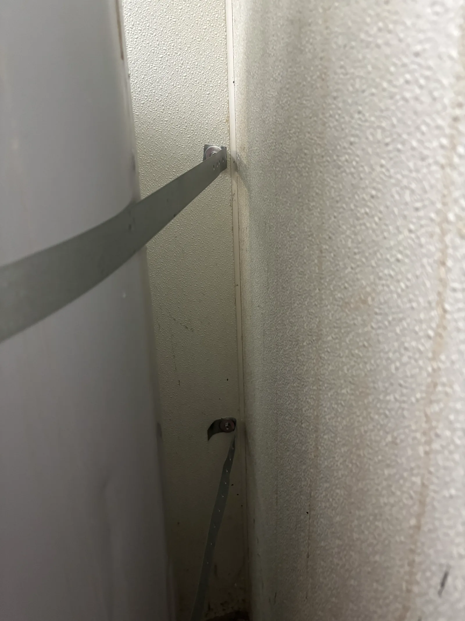 Lower seismic restraint anchor documented in the compact water-heater service area.