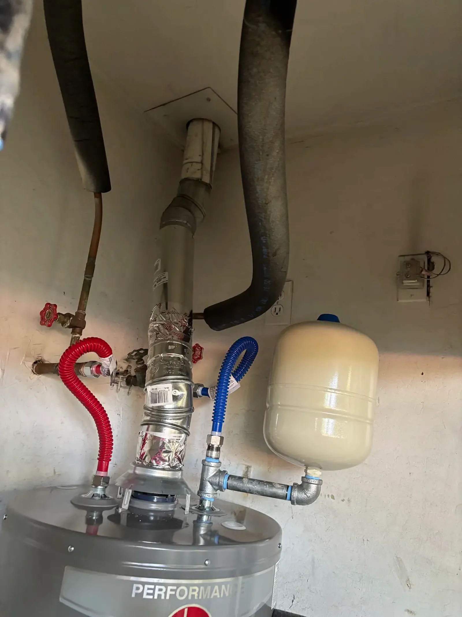Close view of the Roseville water heater replacement showing the upper water connections, expansion tank, and vent connector.