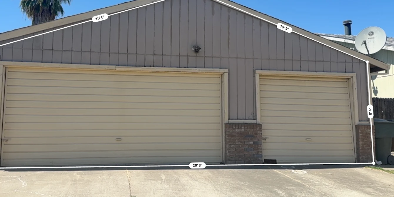 Original vertical siding, garage door surrounds and brick base before the Sacramento siding replacement