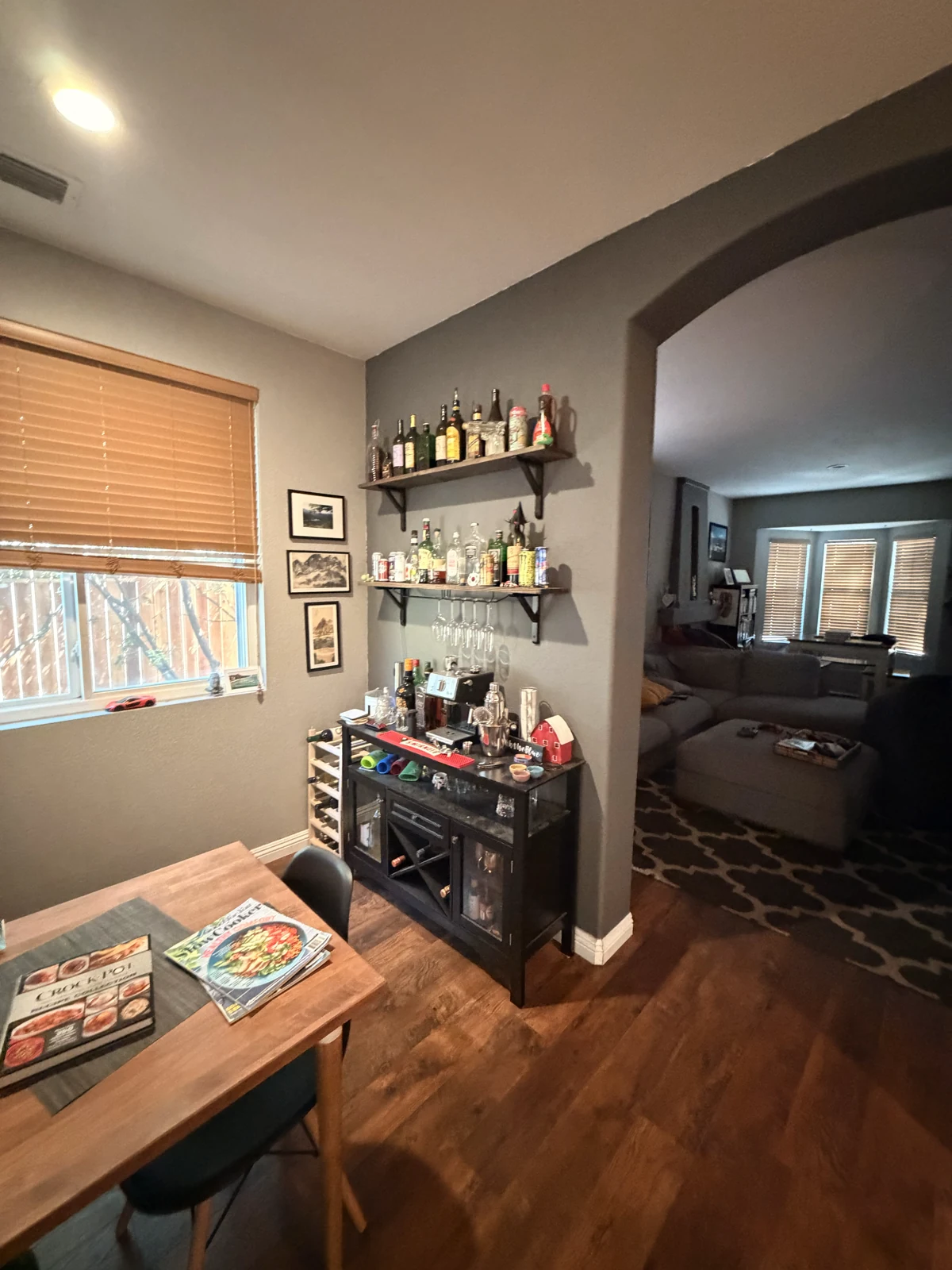 Original bar corner with a freestanding drinks cart and wall shelves before remodeling