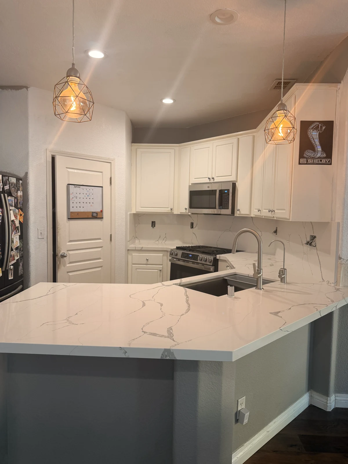 White quartz with gray veining across the single-level peninsula and kitchen counters during installation